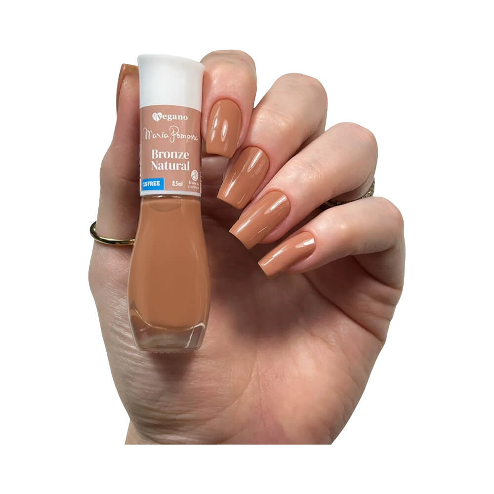 Mão feminina segurando esmalte Maria Pomposa Bronze Natural com unhas pintadas